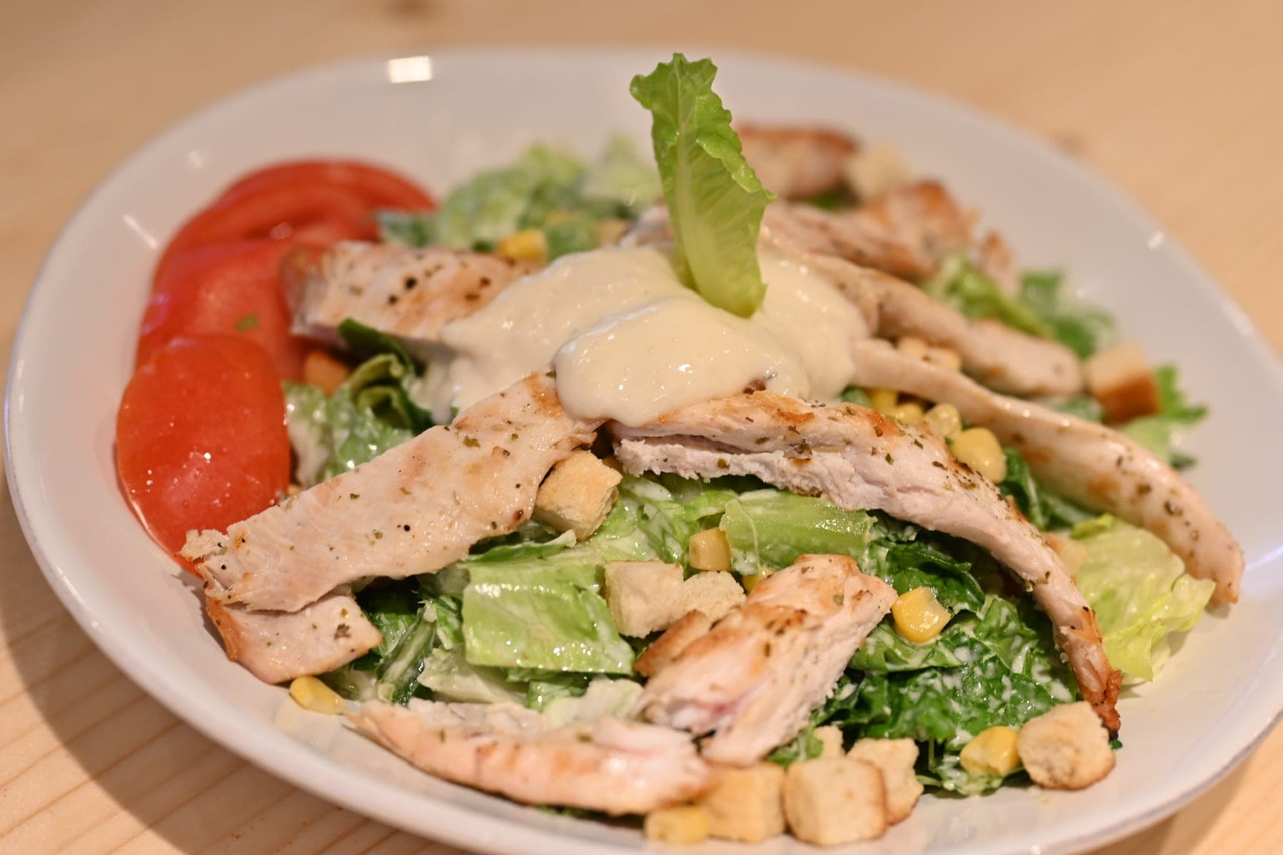 Chicken Caesar salad with tomato, croutons and shaved parmesan.