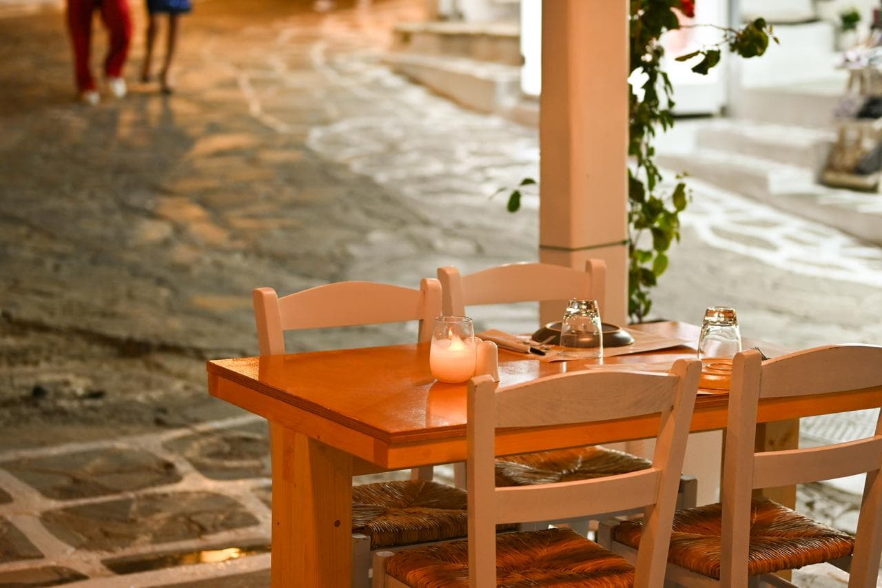 A candlelit table on the stone alley outside Mikri Avra in the evening.